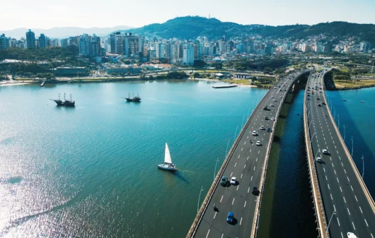 Imagem aérea da Ilha de Santa Catarina durante um dia ensolorado para ilustrar matéria sobre os melhores bairros de Florianópolis