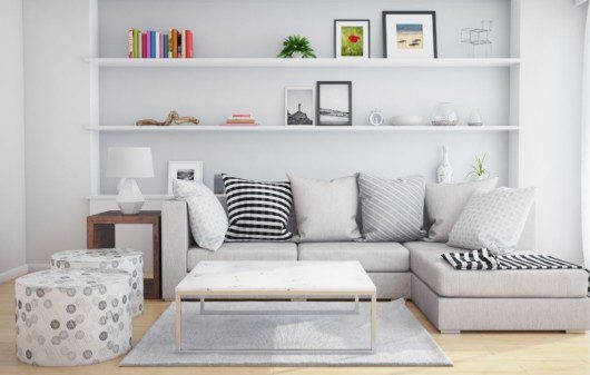 sala de estar, com prateleira ao fundo, cheia de objetos de decoração. Na frente, sofá com almofadas pretas e brancas