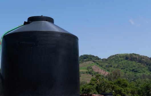 Imagem de uma cisterna grande na cor preta ao ar livre.