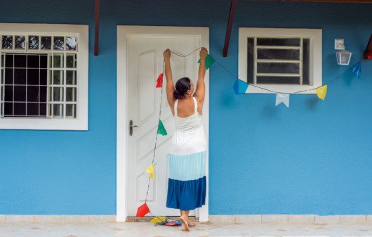 Imagem de uma mulher pendurando bandeirinhas de festa junina.