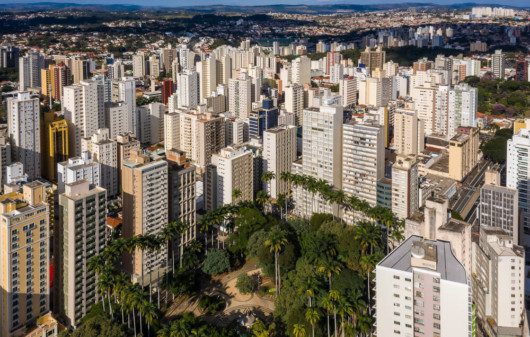 Foto que ilustra matéria sobre o custo de vida em Campinas mostra uma pequena praça arborizada, que é o centro da parte inferior da imagem, vista do alto e cercada de grandes prédios.