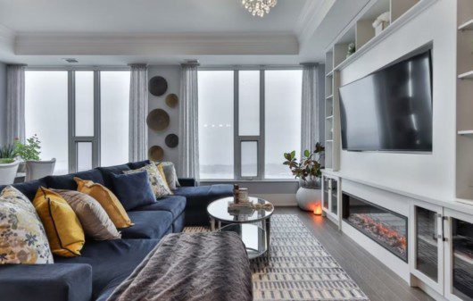 sala de tv pequena com sofá em L, televisão de tela plana, armários embutidos e janelas amplas e claras