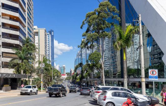 Foto que ilustra matéria sobre o que fazer em Nova Lima mostra uma avenida movimentada do bairro Vila da Serra, onde aparecem prédios grandes e carros.
