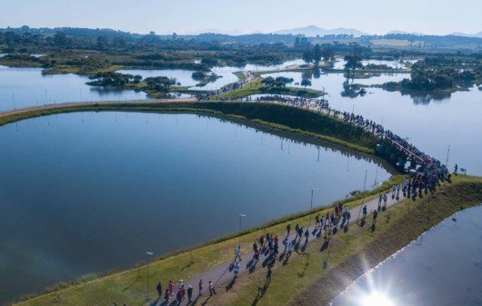 Foto que ilustra matéria sobre parque em Pinhais mostra uma visão do alto de vários lagos do Parque das Águas, com muitas pessoas andando pelos caminhos por entre eles.