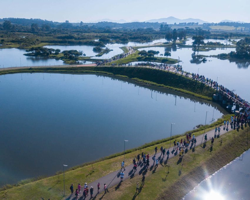 Foto que ilustra matéria sobre parque em Pinhais mostra uma visão do alto de vários lagos do Parque das Águas, com muitas pessoas andando pelos caminhos por entre eles.