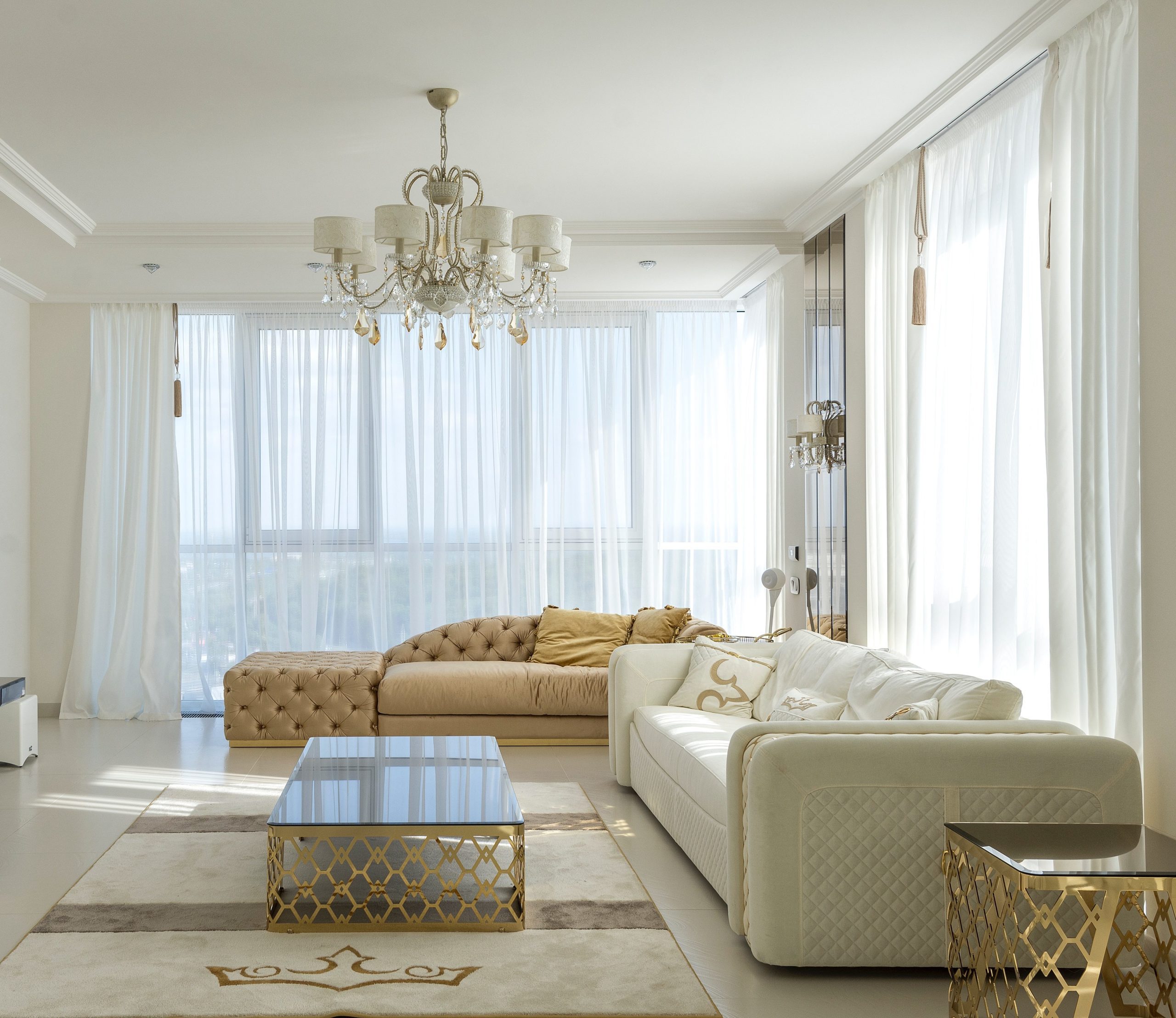 Sala de estar clássica em tons neutros e cortinas em voil branco que levam ainda mais sofisticação ao ambiente. 
