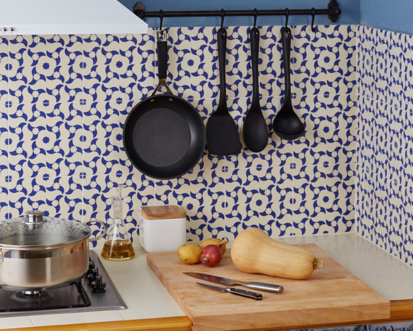 Cozinha revestida com azulejo português com utensílios de cozinha pendurados em ganchos.