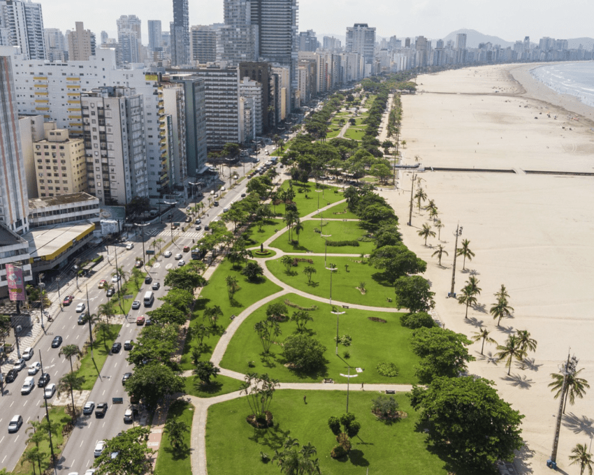 Foto que ilustra matéria sobre orla de Santos mostra a orla da cidade vista de cima, com extensa faixa de areia e uma parte do maior jardim de orla do mundo