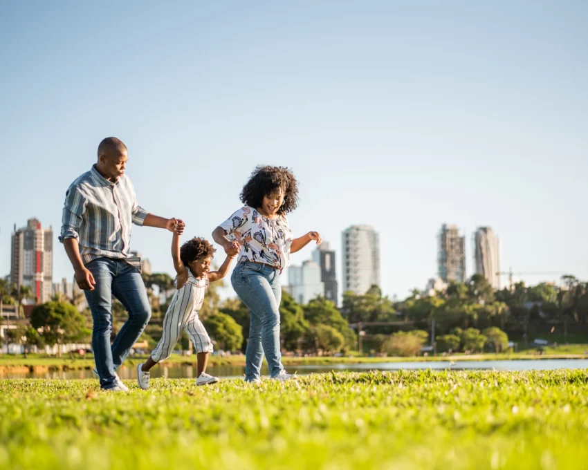 Imagem de uma família, composta por um homem, uma mulher e uma criança pequena, passeando no final da tarde em um parque para ilustrar matéria sobre o ABC Paulista