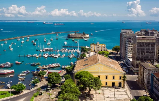 Imagem da vista aérea da Baía de Todos os Santos mostra mar, embarcações, vegetação e prédios para ilustrar matéria sobre os bairros mais populosos de Salvador