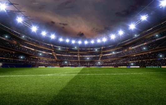 Imagem da estrutura de um estádio de futebol vista do campo mostra arquibancadas e iluminação para ilustrar matéria sobre estádios em São Paulo