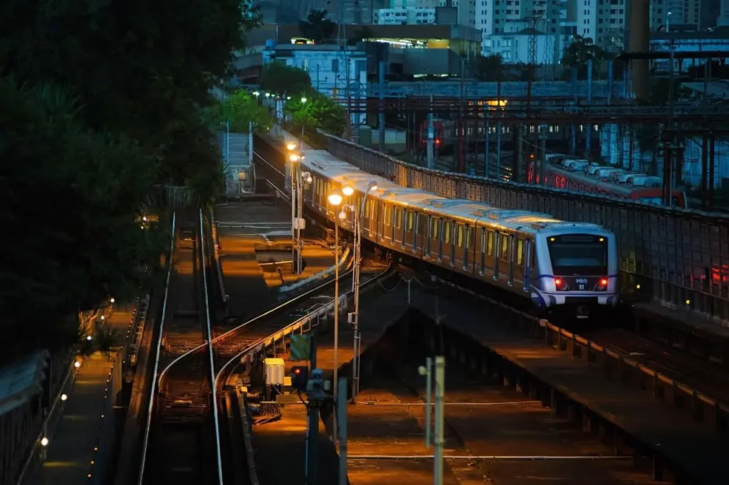 Imagem de um trem do metrô passando pelos trilhos de uma estação no fim de tarde para ilustrar matéria sobre a Linha 2-Verde, que compõe uma das rotas do sistema metroviário da cidade de São Paulo