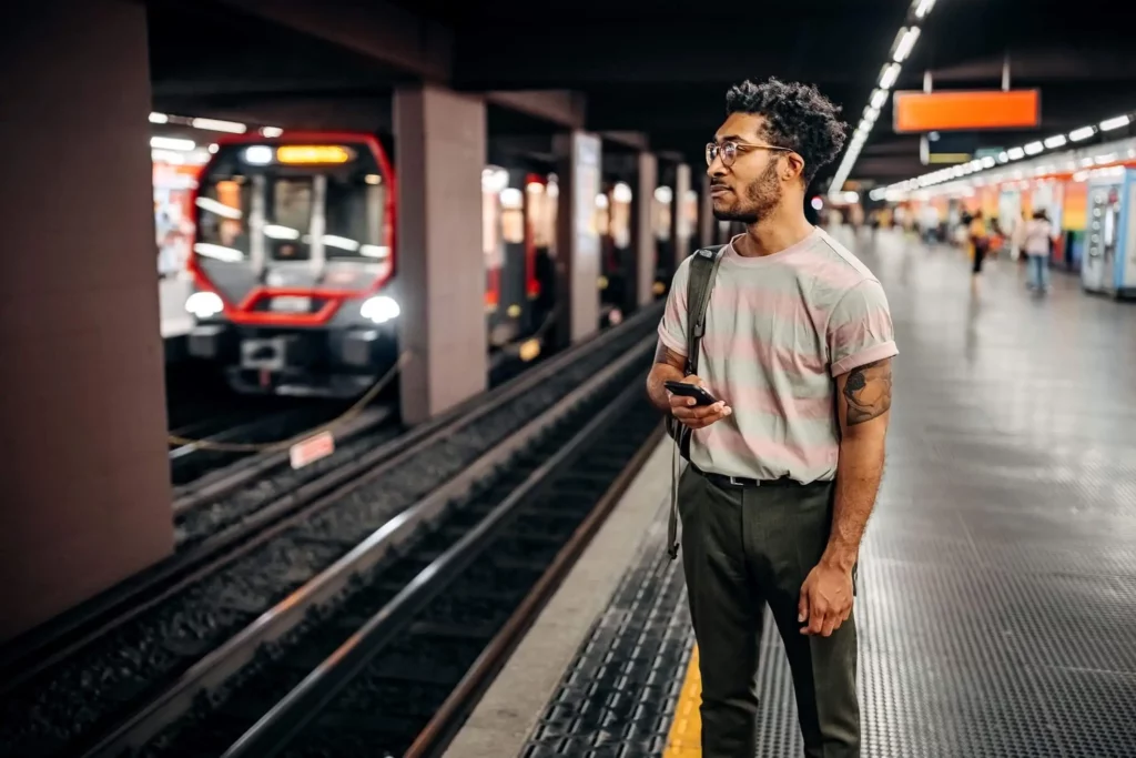Imagem de um um homem com celular na mão esperando a chegada no metrô na estação para ilustrar matéria a Linha 3-Vermelha do metrô de SP