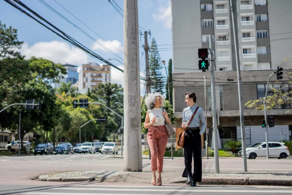 Imagem de duas pessoas atravessando a faixa de pedestre com um copo de café na mão para ilustrar matéria sobre qual o bairro mais populosos do Paraná