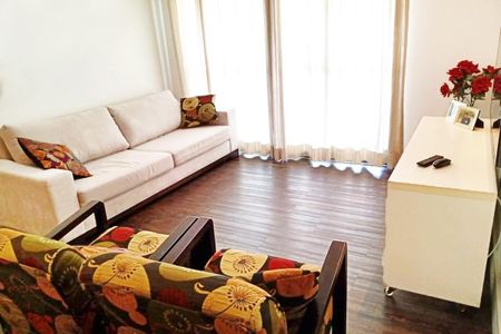 Sala com sofá e cadeira de madeira, com janelas grandes e iluminação natural, com um tom de madeira escuro no piso e uma mesa branca com um vaso de rosas vermelhas. de apartamento à venda com 3 quartos, 92m² em Anhangabaú, Jundiaí