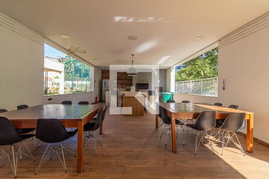 Sala de reuniões com mesa de madeira e cadeiras de plástico, iluminação natural e vista para a rua. de apartamento à venda com 2 quartos, 65m² em Jardim Umuarama, São Paulo