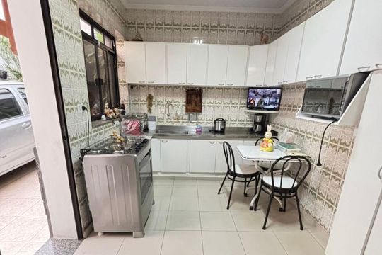 Cozinha com móveis brancos e fogão de aço inox, com mesa e cadeiras para refeições, iluminada com boa qualidade de luz, bem decorada e em bom estado de conservação. de casa à venda com 4 quartos, 170m² em Cambuci, São Paulo