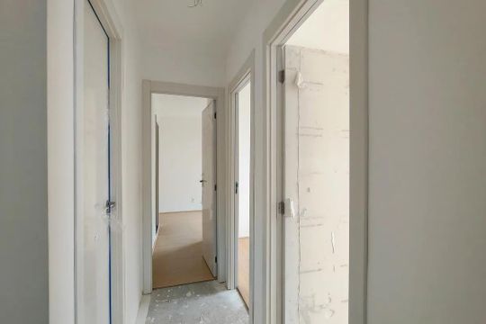 Corredor com portas e paredes brancas, com um chão de concreto e um piso de madeira no final. de apartamento à venda com 3 quartos, 69m² em Santo Cristo, Rio de Janeiro