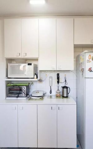 Apartamento à venda com 77m², 3 quartos e 1 vagaCozinha com geladeira, fogão e micro-ondas, com iluminação adequada e mobiliário simples.