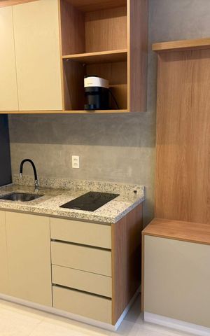 Studio à venda com 25m², 1 quarto e sem vagaCozinha com geladeira e fogão, com móveis de madeira e piso de porcelanato.