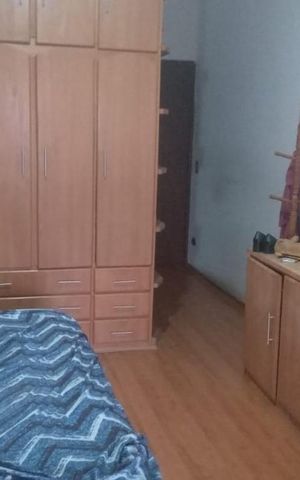 Casa à venda com 130m², 3 quartos e 2 vagasQuarto com móveis de madeira e cama com cobertor azul e branco.
