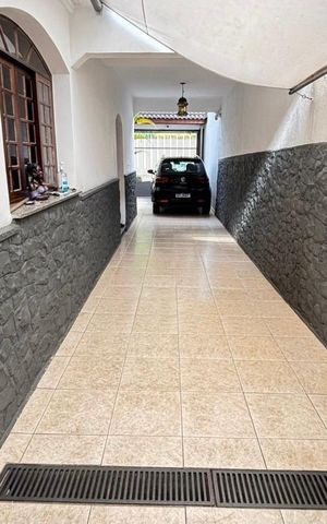 Casa à venda com 170m², 4 quartos e 5 vagasPátio com garagem e entrada para casa, com piso de cerâmica e parede de pedra.