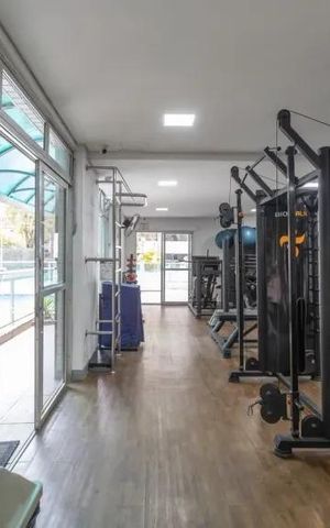 Apartamento à venda com 60m², 2 quartos e 2 vagasGinásio com equipamentos de treino e vista para piscina.