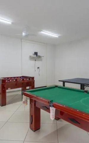 Apartamento à venda com 60m², 2 quartos e 2 vagasSala de jogos com mesa de bilhar, mesa de ping-pong e mesa de futebol, com sofá e iluminação adequada.
