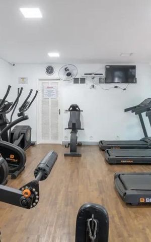 Apartamento à venda com 60m², 2 quartos e 2 vagasSala de ginástica com equipamentos de treino e televisão.