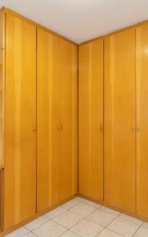 Apartamento à venda com 60m², 2 quartos e 2 vagasCabinete de madeira claro com prateleiras e portas, em uma sala com piso de porcelanato e porta branca.