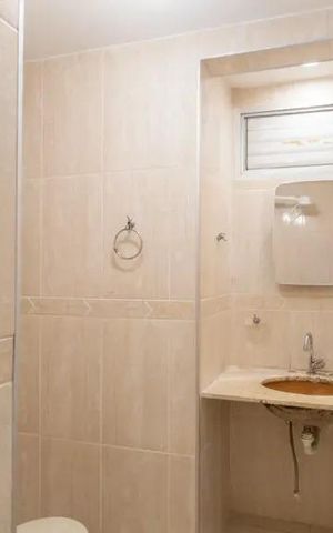 Apartamento à venda com 60m², 2 quartos e 2 vagasBanheiro com piso de porcelanato, pia e vaso sanitário brancos, e uma janela pequena.
