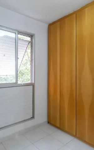 Apartamento à venda com 60m², 2 quartos e 2 vagasQuarto com móveis de madeira e janela com persianas de alumínio.