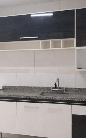 Apartamento à venda com 69m², 2 quartos e 1 vagaCozinha com móveis brancos e pretos, piso de porcelanato e balcão de granito.