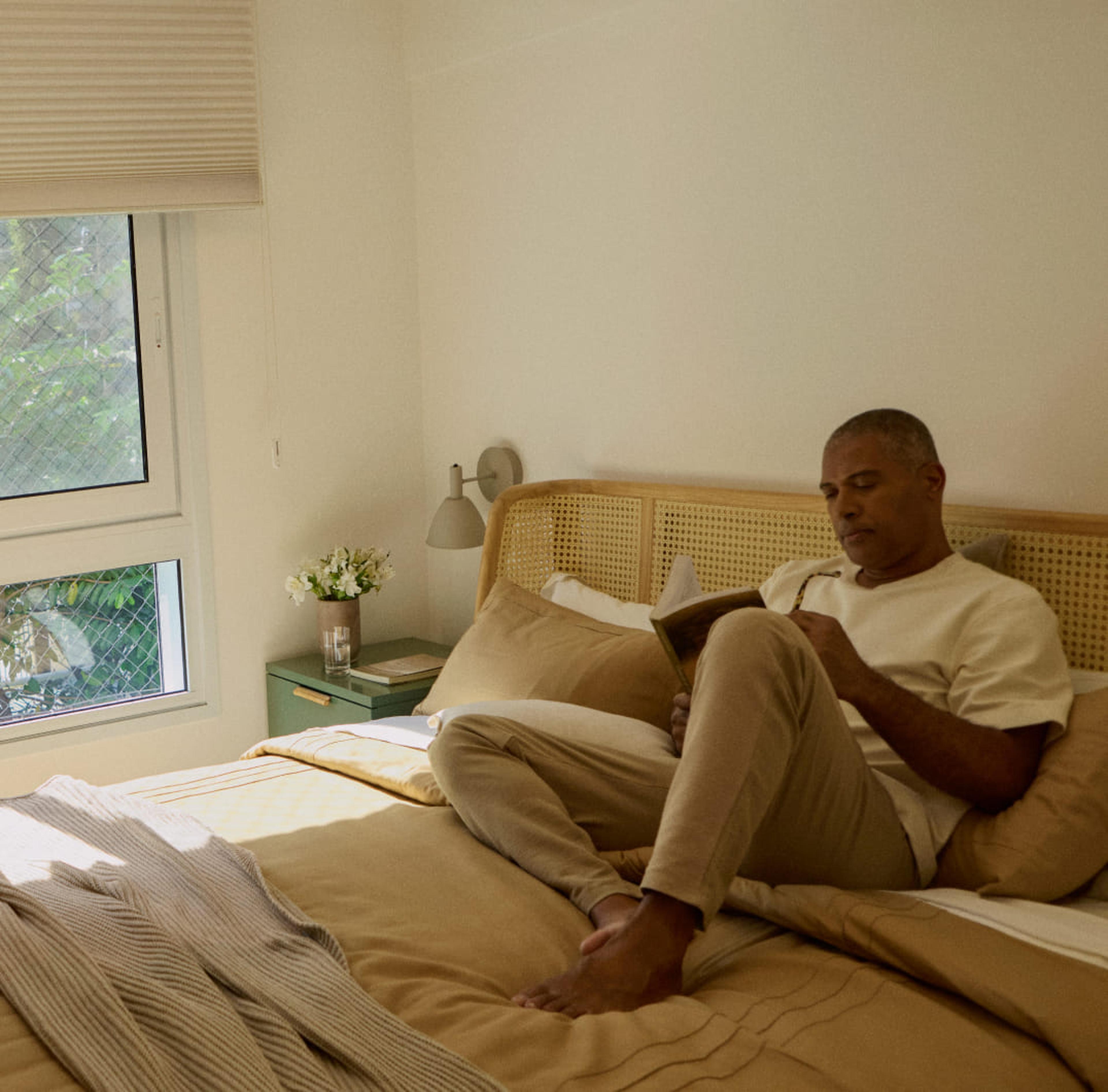 Homem organizando a estante da casa, com caixas de papelão de mudança ao fundo