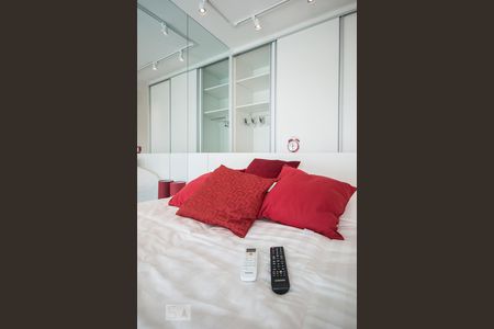 Detalhe em primeiro plano da cama com os controles de TV e Ar condicionado e em segundo plano os cabides dentro do armário embutido de apartamento para alugar com 1 quarto, 35m² em Cidade Monções, São Paulo
