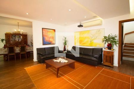 Sala com móveis de couro, pinturas e uma mesa de centro com objetos decorativos. de casa à venda com 4 quartos, 400m² em Pinheiros, São Paulo