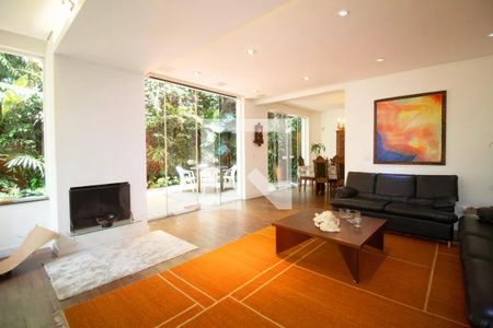 Sala com decoração moderna e vista para o jardim, com uma lareira e uma mesa de jantar. de casa à venda com 4 quartos, 400m² em Pinheiros, São Paulo
