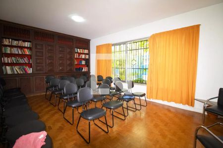 Sala com móveis de madeira, prateleiras de livros e janelas com cortinas amarelas. de casa à venda com 4 quartos, 400m² em Pinheiros, São Paulo