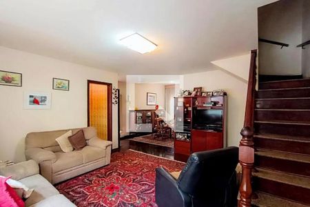 Sala com sofás, televisão e móveis de madeira, com uma escada de madeira no fundo. de casa à venda com 3 quartos, 142m² em Alto da Lapa, São Paulo