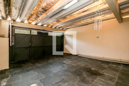 Garagem com portas de metal e piso de pedra, iluminada por luzes fluorescentes. de casa à venda com 4 quartos, 180m² em Umuarama, Osasco