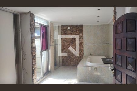 Banheiro com piso de porcelanato, banheira e chuveiro, e porta de madeira. de casa à venda com 4 quartos, 200m² em Jardim Santo Eduardo, Guarulhos