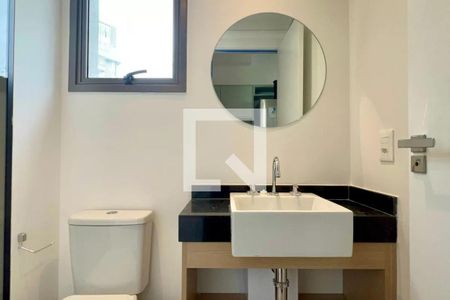 Banheiro com pia e vaso sanitário, com janela e espelho redondo. de apartamento à venda com 1 quarto, 24m² em Pompeia, São Paulo