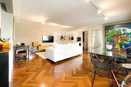 Sala de estar com sofá branco, mesa de vidro e cadeiras de metal, parede com TV e guitarras penduradas, piso de madeira parquet. de apartamento à venda com 4 quartos, 105m² em Cerqueira César, São Paulo
