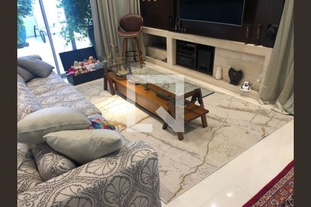 Sala com sofá, mesa de vidro e TV em parede com decoração de madeira e pedra. de apartamento à venda com 6 quartos, 220m² em Santo Amaro, São Paulo