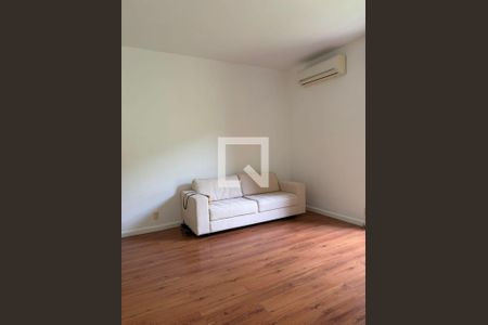 Sala com sofá branco e piso de madeira, com ar condicionado na parede. de apartamento para alugar com 3 quartos, 100m² em Gávea, Rio de Janeiro