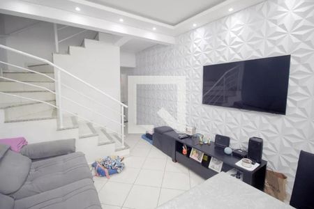 Sala com TV e sofá, com decoração em tons de branco e cinza, com uma escada em fundo branco e uma parede com design tridimensional. de casa à venda com 3 quartos, 100m² em Campestre, Santo André