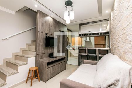 Sala de estar com sofá, TV e mesa de madeira, iluminada por lâmpadas de design moderno. de casa à venda com 2 quartos, 74m² em Vila Santa Edwiges, São Paulo