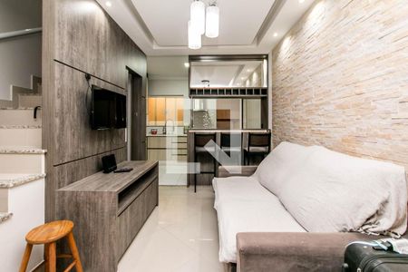 Sala de estar com sofá, TV e mesa de madeira, iluminada por lâmpadas de design. de casa à venda com 2 quartos, 74m² em Vila Santa Edwiges, São Paulo