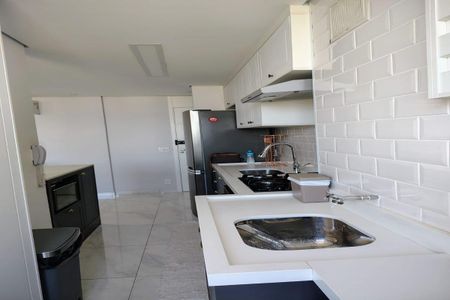 Apartamento à venda com 93m², 3 quartos e 2 vagasCozinha moderna com móveis brancos e azuis, iluminada por luz natural e artificial, com piso de porcelanato e bancada de granito.