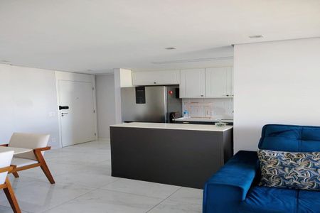 Apartamento à venda com 93m², 3 quartos e 2 vagasSala com sofá azul, mesa e cadeiras, cozinha com geladeira e fogão, piso de porcelanato e iluminação boa.